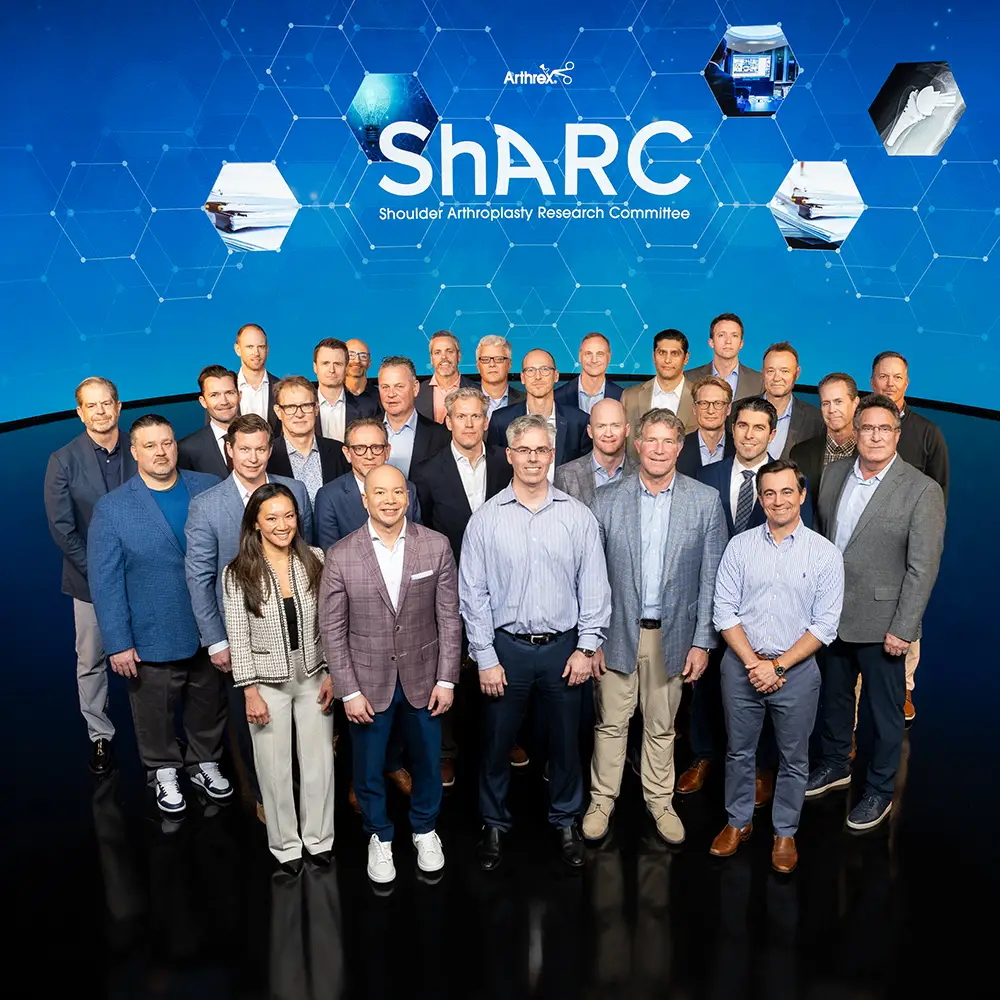 Group photo of the Shoulder Arthroplasty Research Committee standing in front of a blue background with the Arthrex logo.
