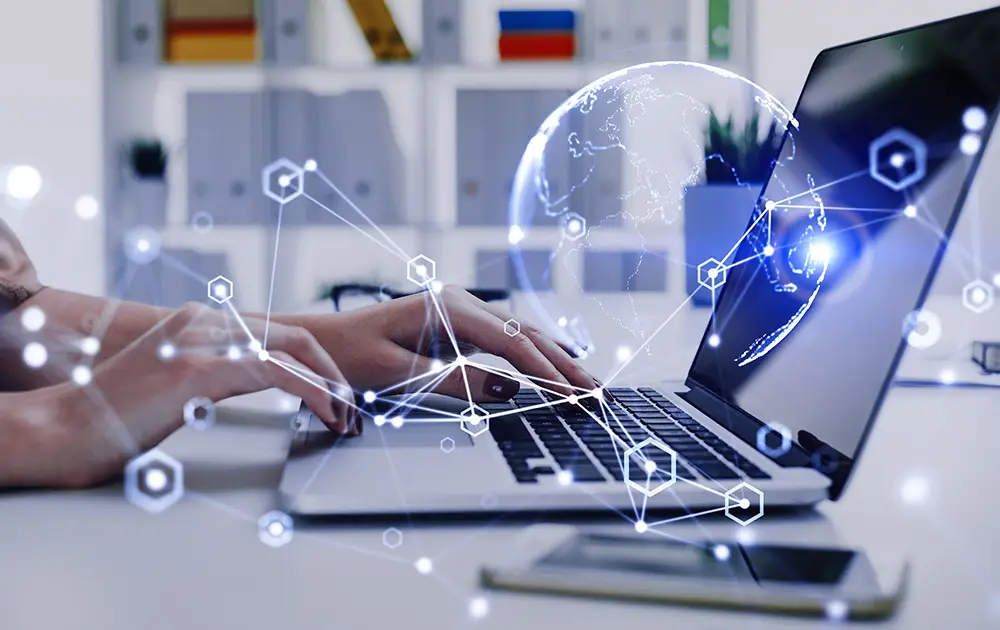 A hand types on a laptop keyboard while digital synergies and data visualizations overlay the image.