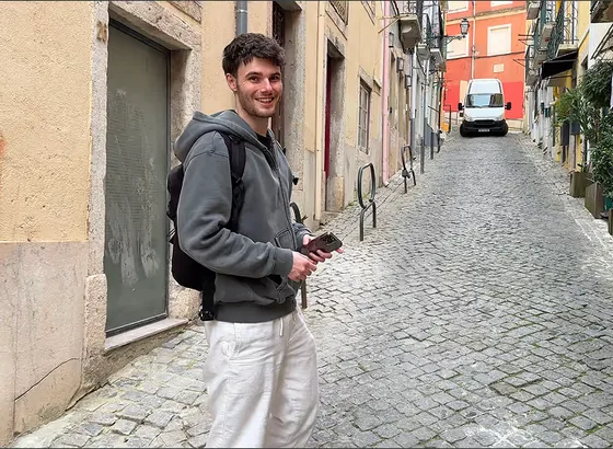 A smiling Noqode team member in a cobbled street, phone in hand