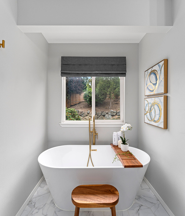modern, luxurious upgrade featuring a freestanding white soaking tub with a gold faucet