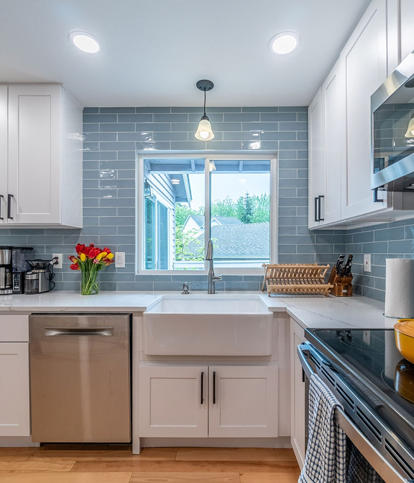 modern, bright space featuring white shaker cabinets, quartz countertops, stainless steel appliances, and a large farmhouse sink