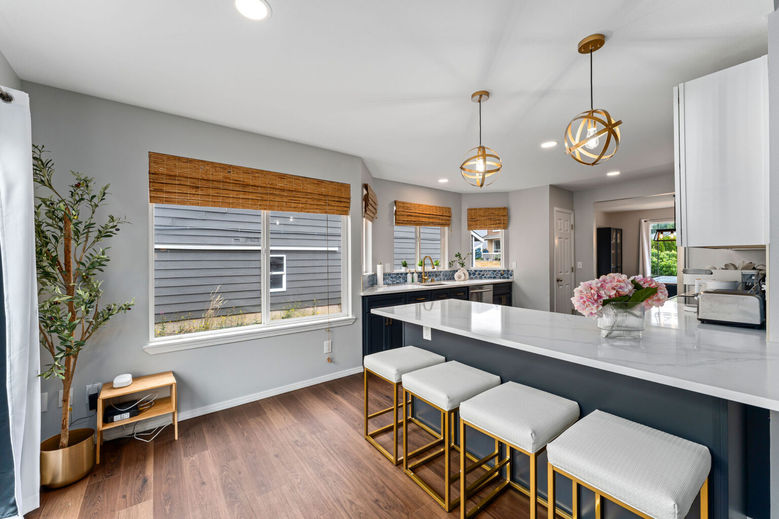 Stylish kitchen with a large white quartz peninsula featuring gold-accented white barstools