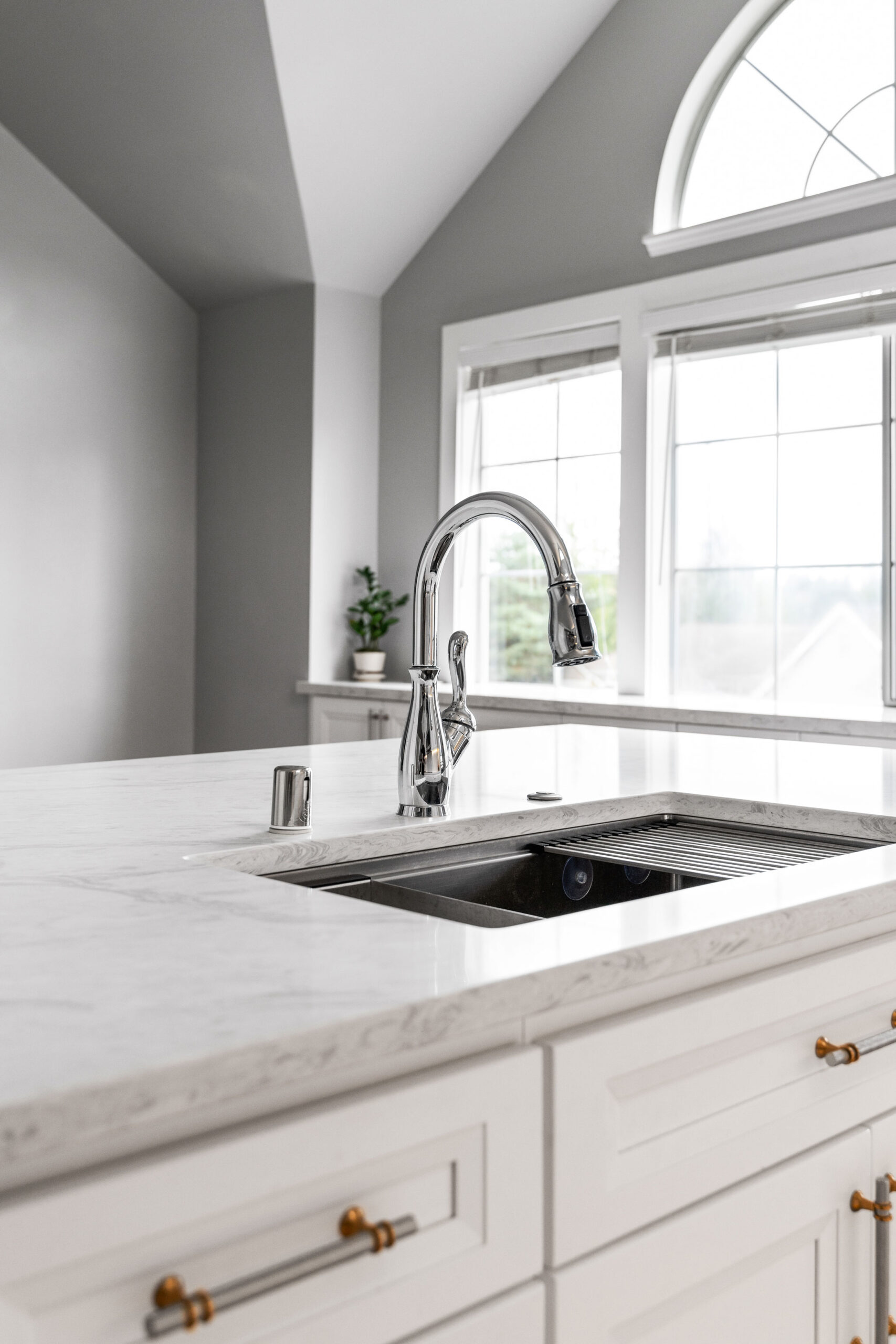 Close-up of a modern kitchen island with a marble countertop, stainless steel undermount sink, and a sleek chrome pull-down faucet