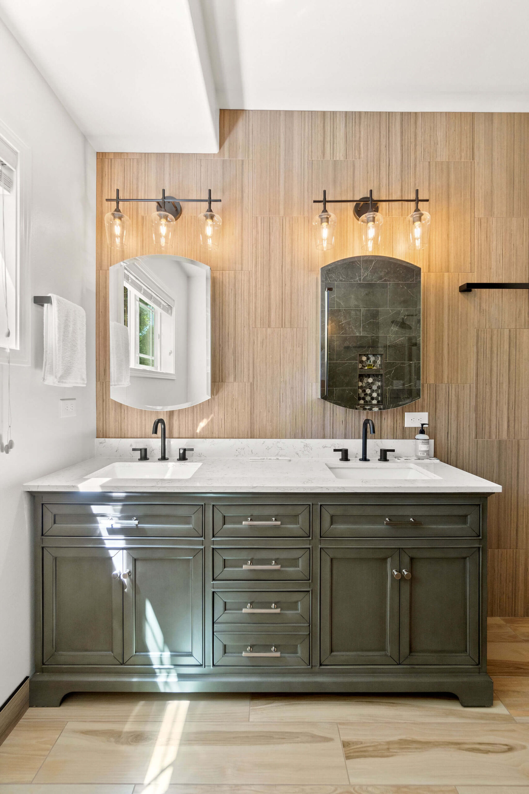 Elegant bathroom vanity with a sage green double-sink cabinet, white marble countertop, and matte black fixtures