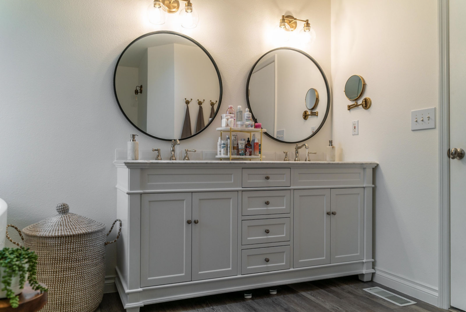Elegant bathroom vanity with dual sinks and round black-framed mirrors, featuring