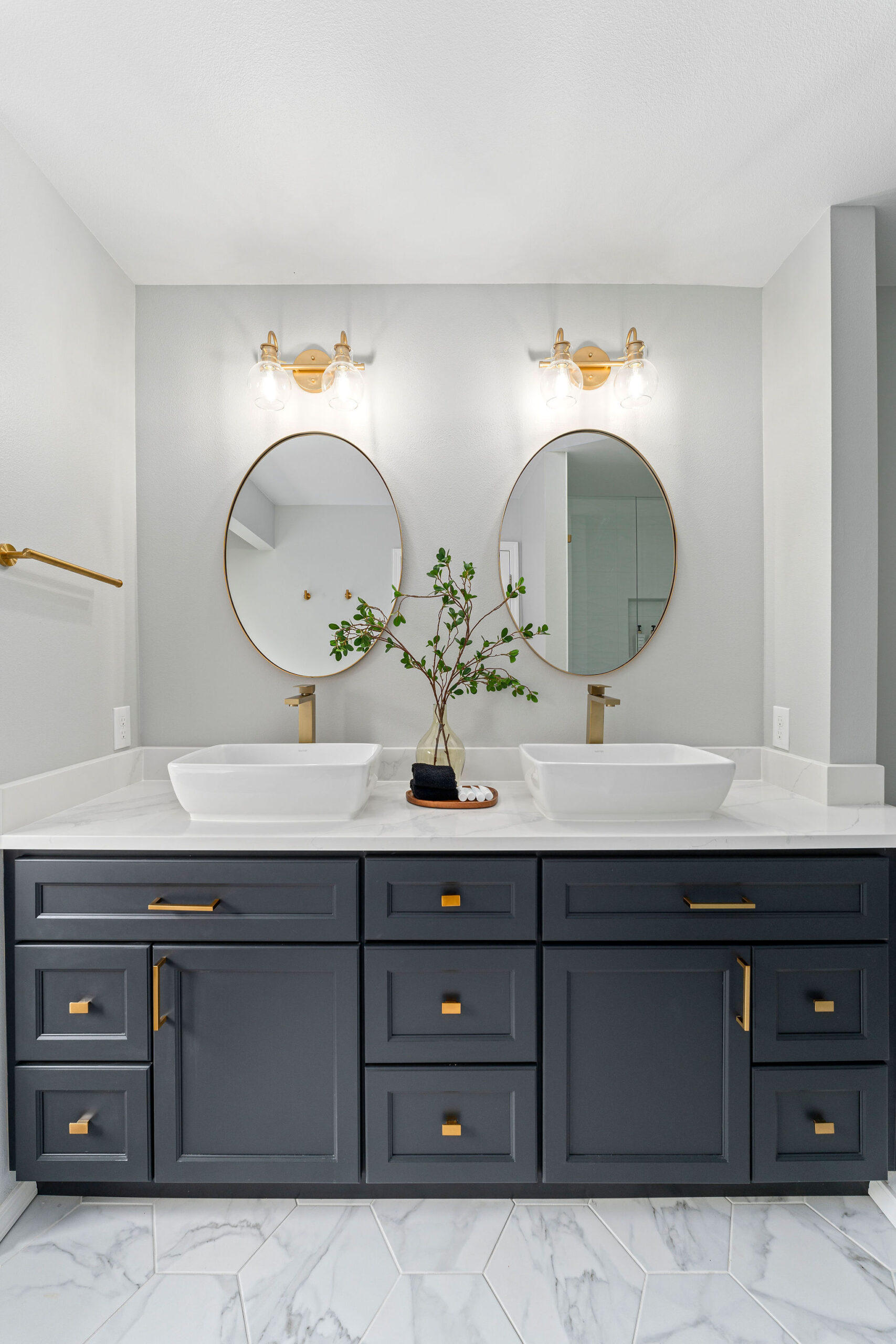 Modern double vanity bathroom with navy blue shaker-style cabinets, white marble countertop