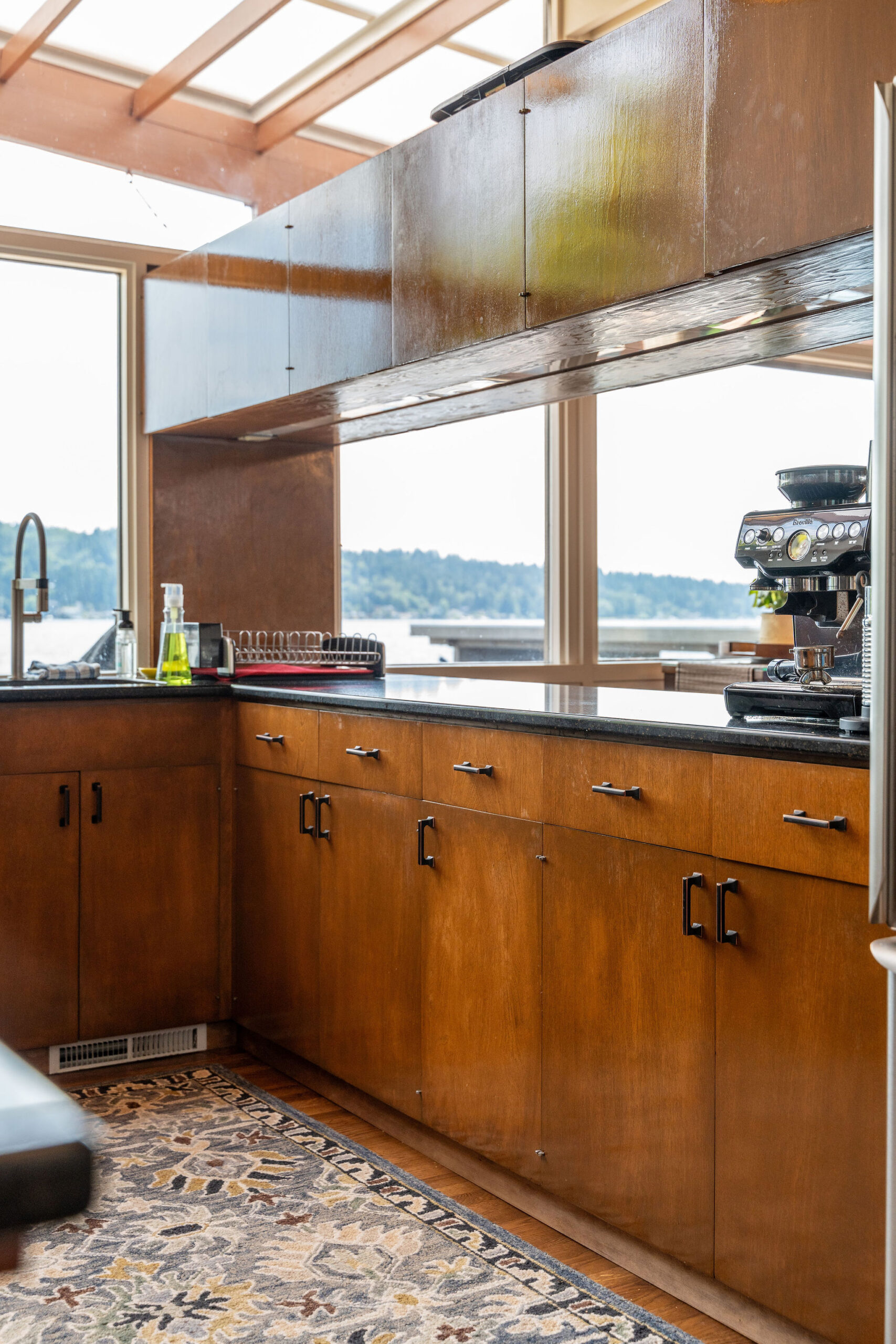 A mid-century modern kitchen featuring warm wood cabinetry, matte black hardware, and black countertops