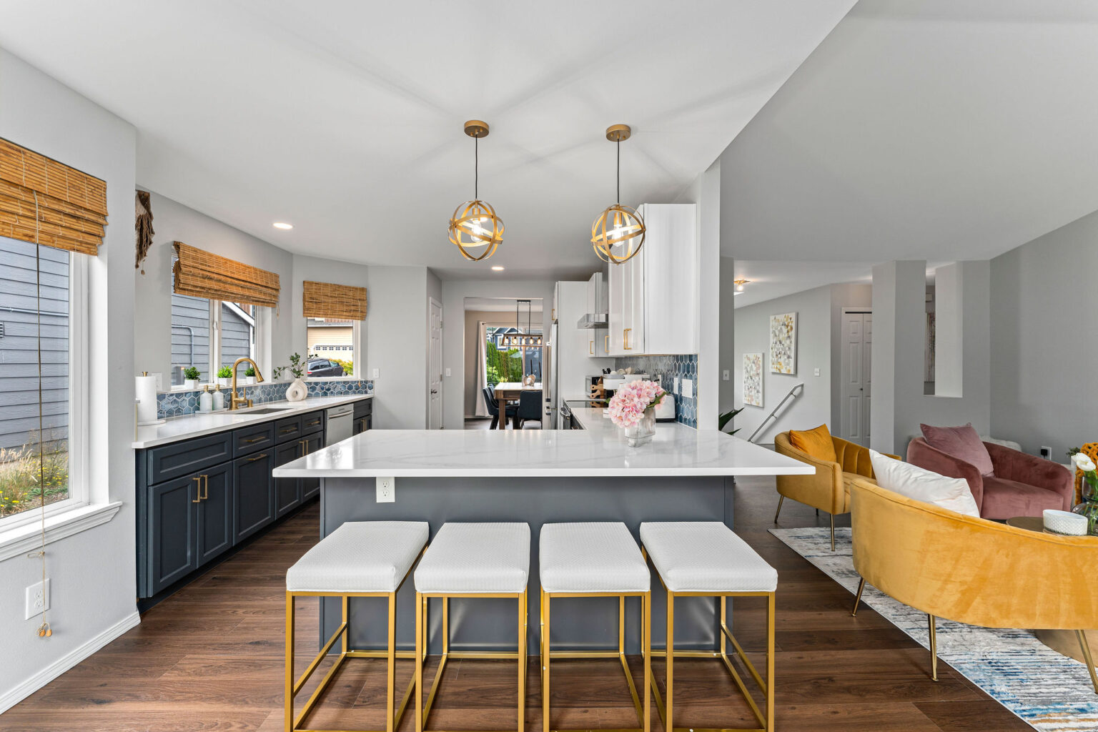 Open-concept modern kitchen and living space featuring a large white quartz island with gold and white bar stools