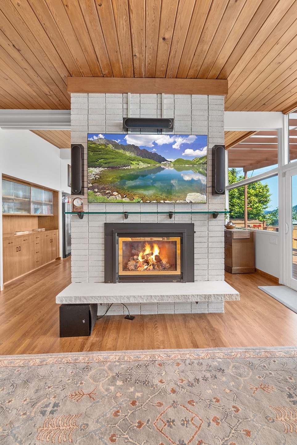 Modern living room featuring a white painted brick fireplace with a built-in wood-burning insert and a mounted flat-screen TV above