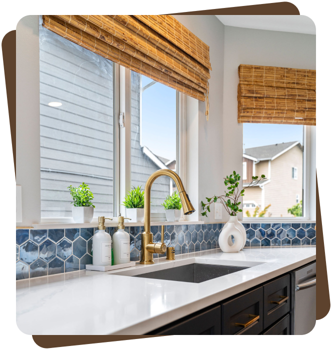 Close-up of a modern kitchen sink area featuring a matte black undermount sink with a sleek brushed gold pull-down faucet
