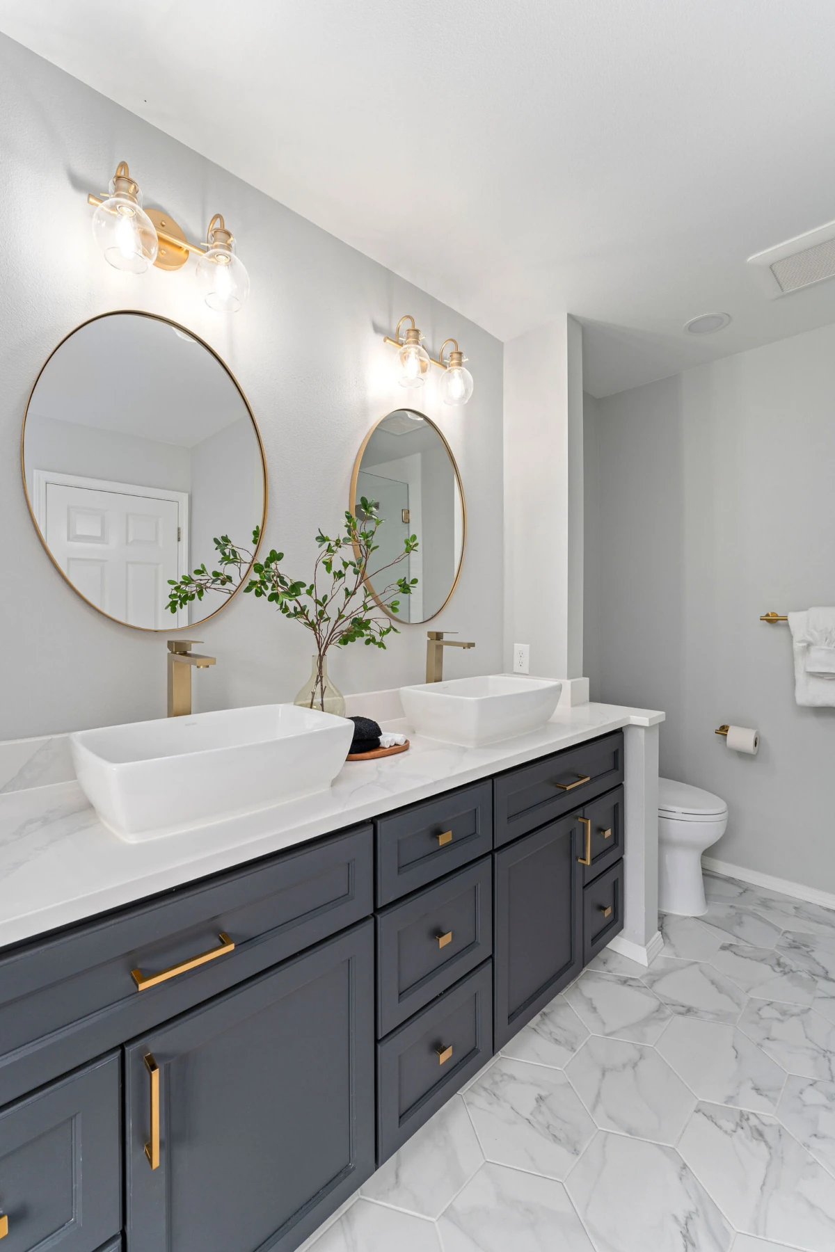 Elegant bathroom featuring a double vanity with navy blue shaker cabinets, gold hardware, and white rectangular vessel sinks