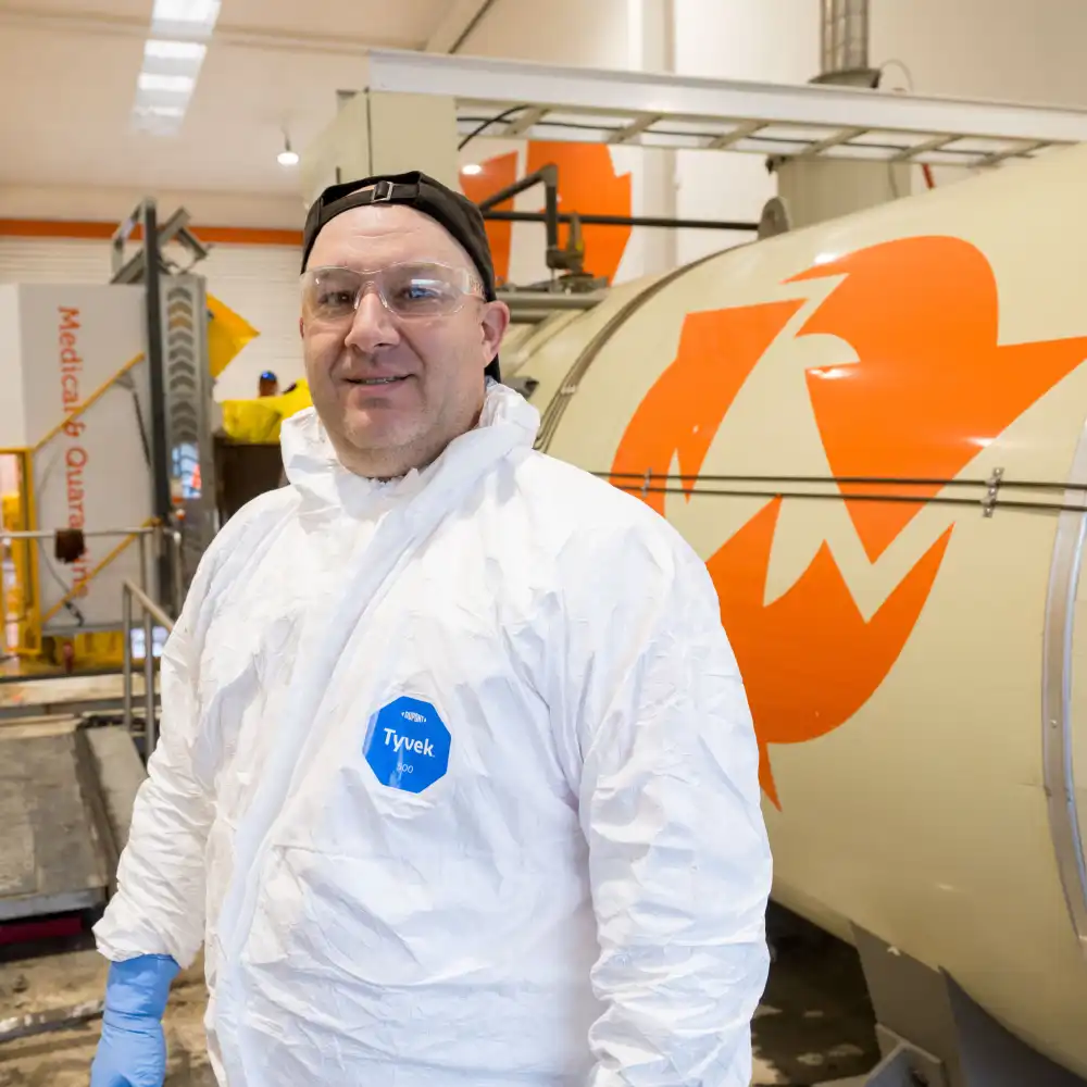 A WasteCo team member in protective gear working with medical & quarantine waste