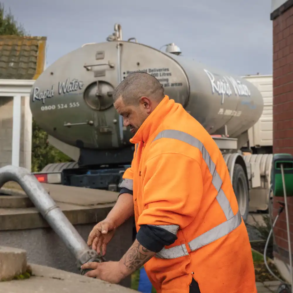 A WasteCo team member filling a water tank with fresh water