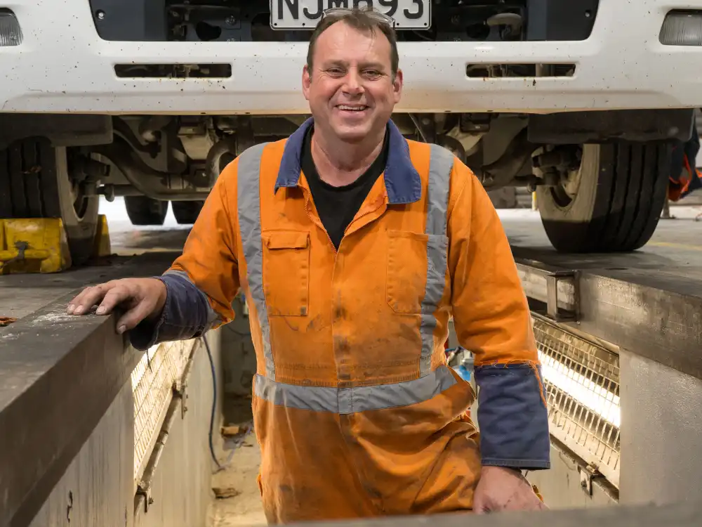 A WasteCo team member performing maintenance on a WasteCo vehicle