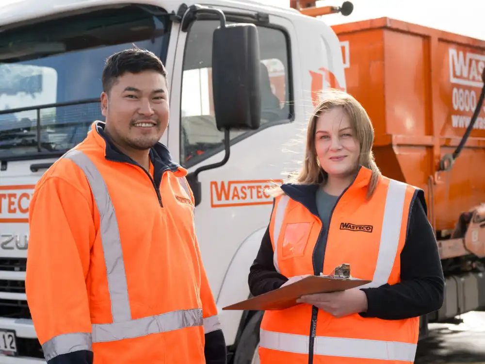 Two WasteCo team members standing in front of a skip truck