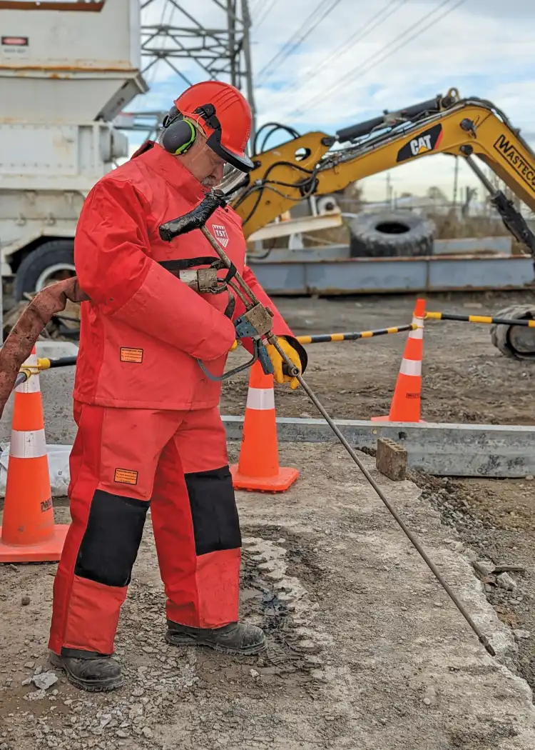 A WasteCo team member operating a high-pressure blaster