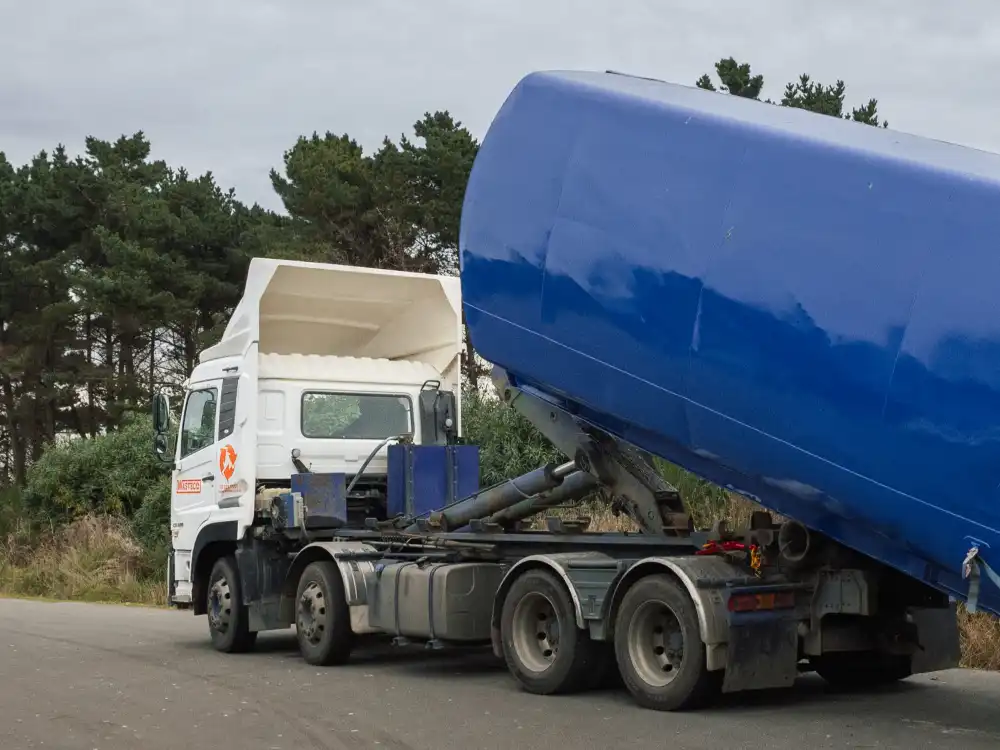 A WasteCo truck lifting a hook bin into place