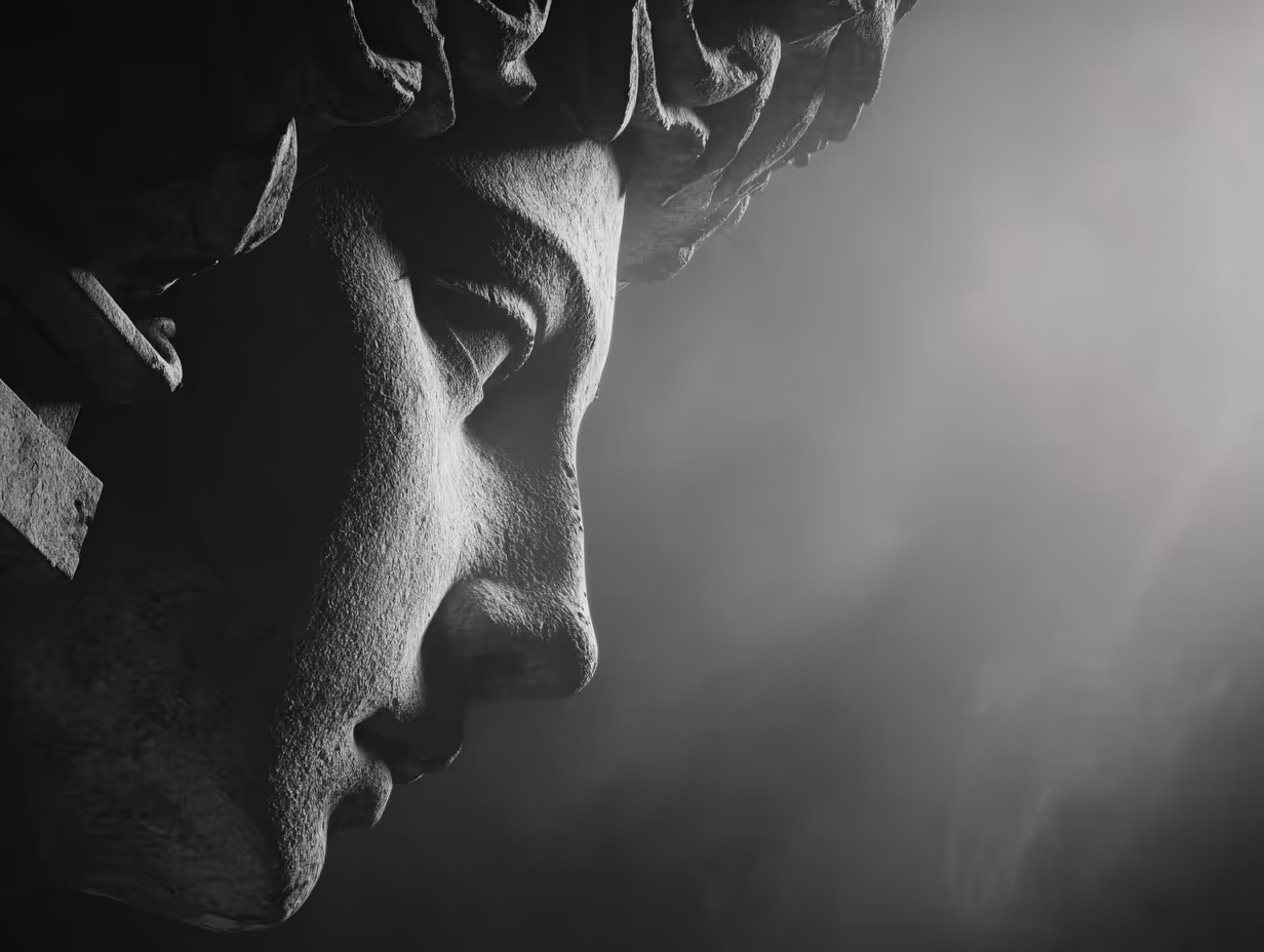 Close-up side view of a classical stone statue's face with detailed texture in dramatic black and white lighting.