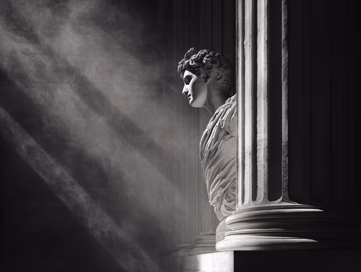 Side view of a classical marble statue bust illuminated by rays of light beside a large fluted column.