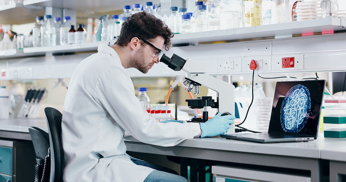 A scientist in his lab using a microscope
