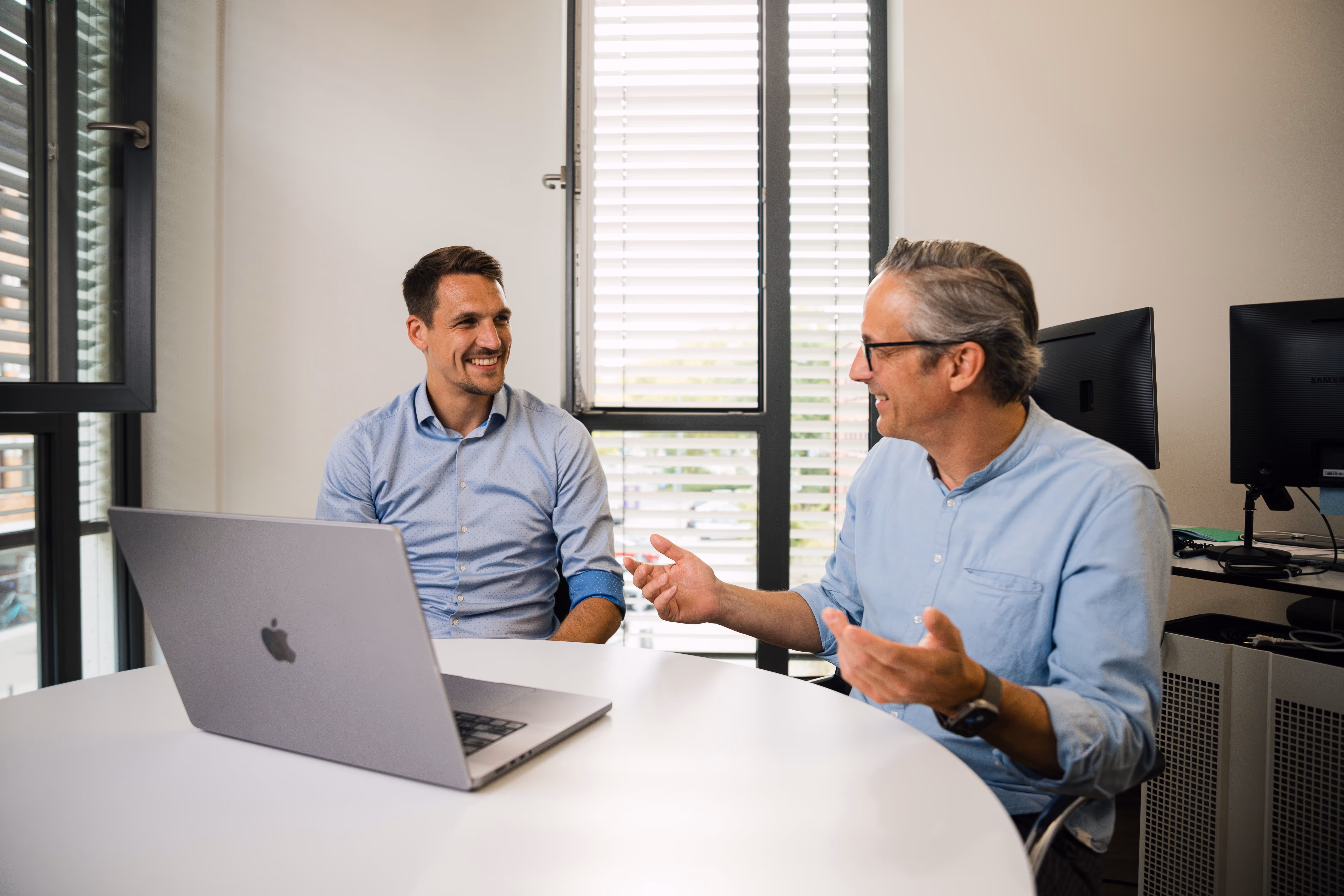 Persönliche Finanzberatung in modernem Büro – zwei Berater im Gespräch über individuelle Strategien für finanzielle Sicherheit und Zukunftsplanung