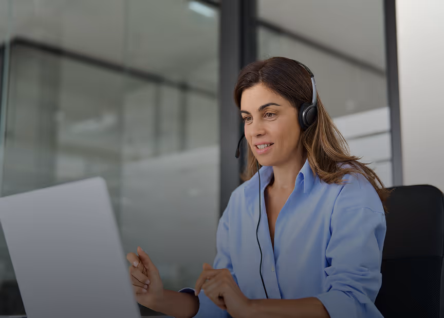Customer support agent working on laptop with headset in modern office