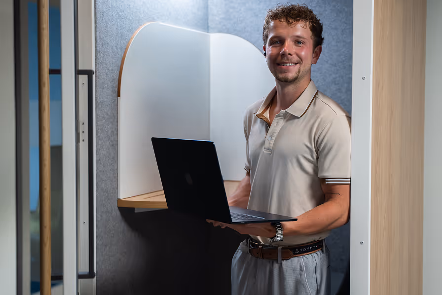 Young professional working remotely with laptop in modern booth workspace