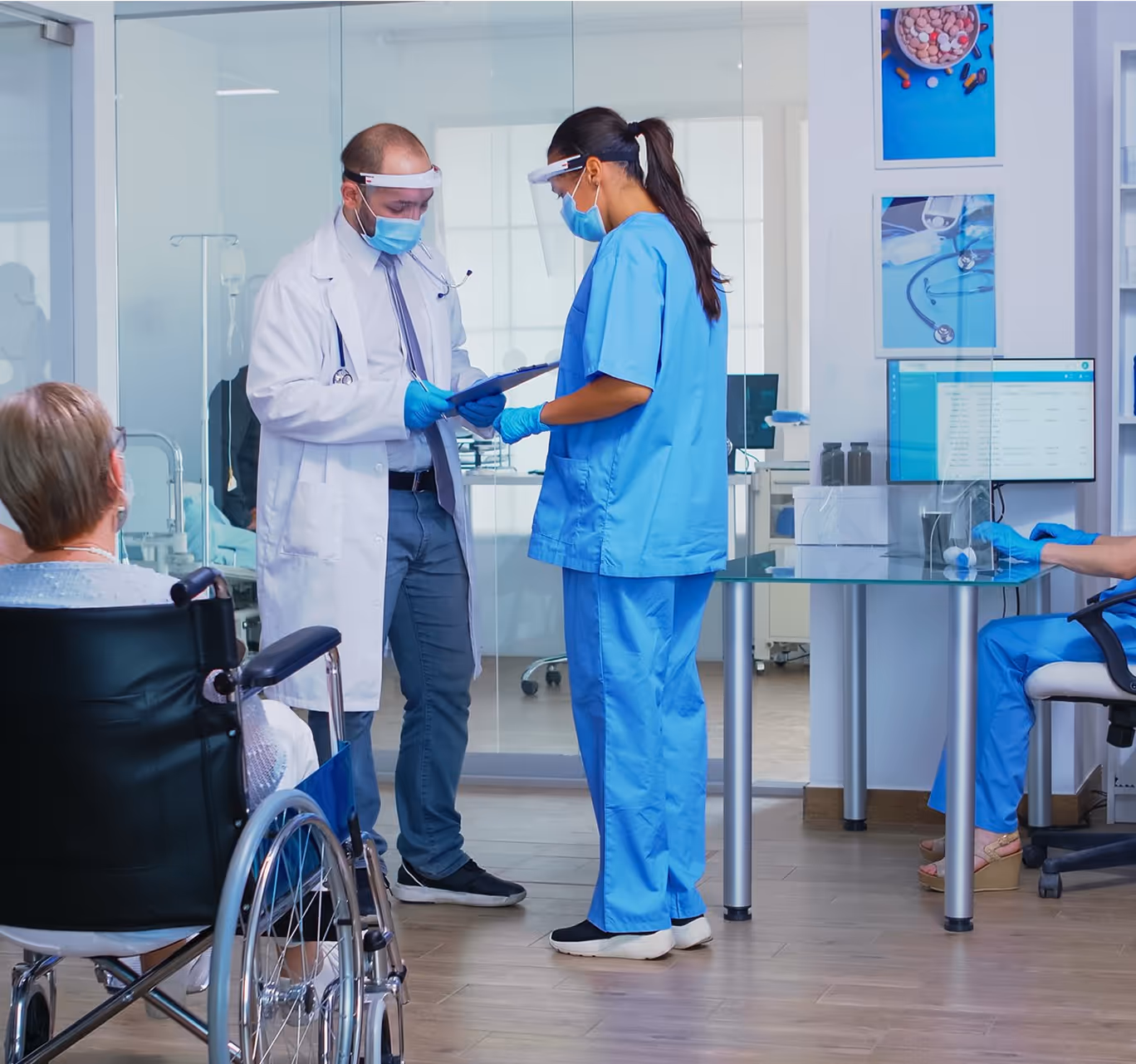 Doctor and nurse discussing medical chart in hospital with patient in wheelchair