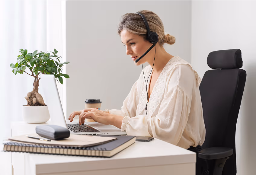 Remote customer support agent working on laptop with headset