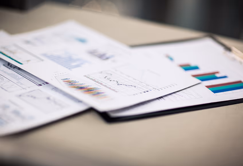 Close-up of printed business reports with bar charts and line graphs on a desk.