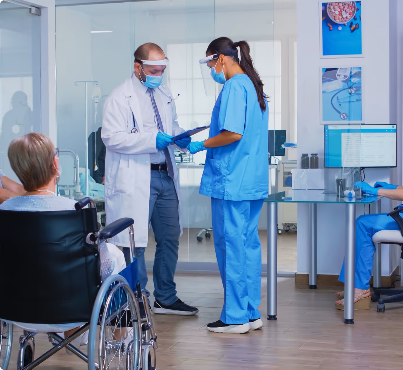 Doctor and nurse discussing medical chart in hospital with patient in wheelchair
