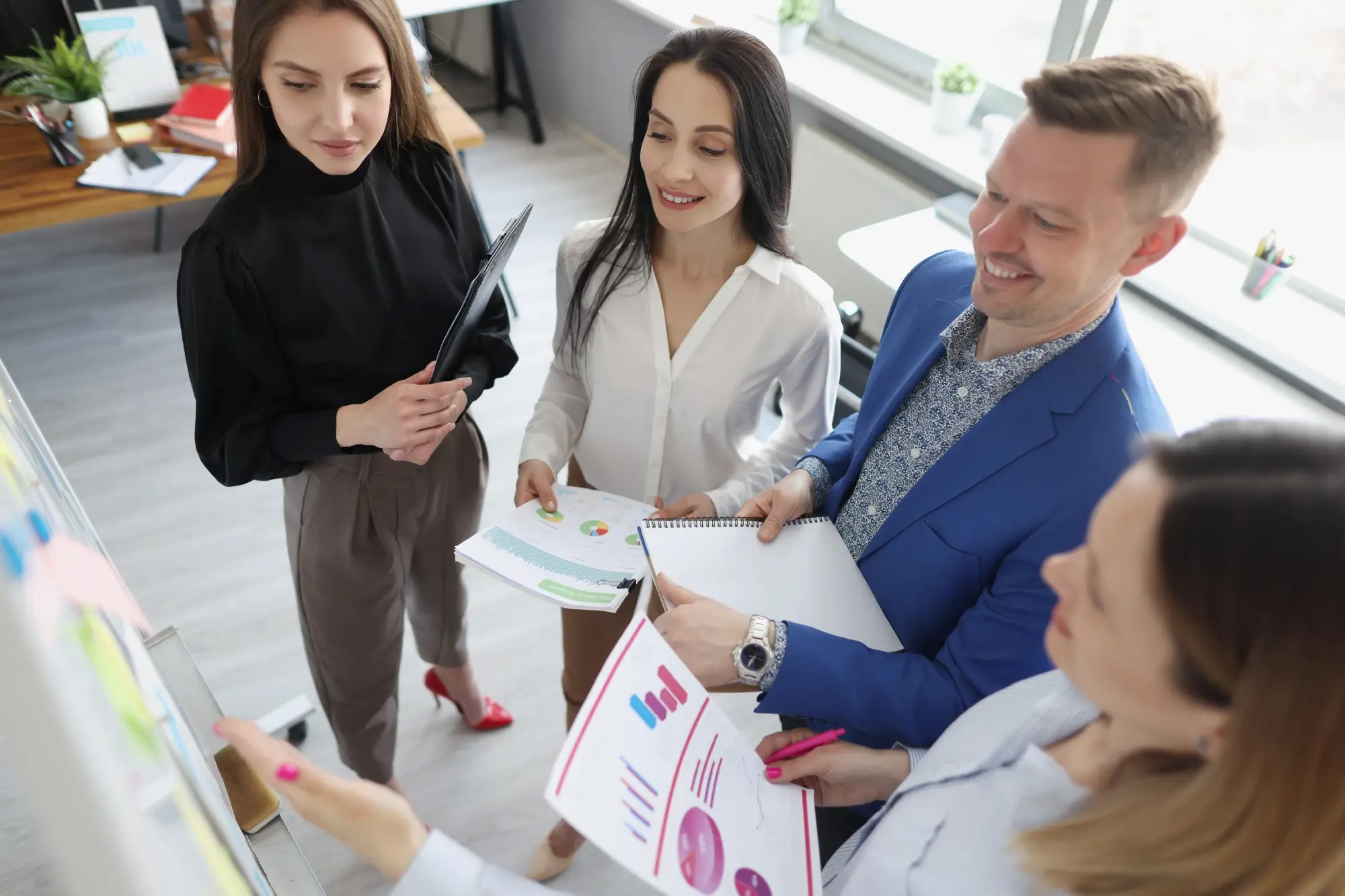 Four colleagues in office discussing charts and documents during a team meeting.