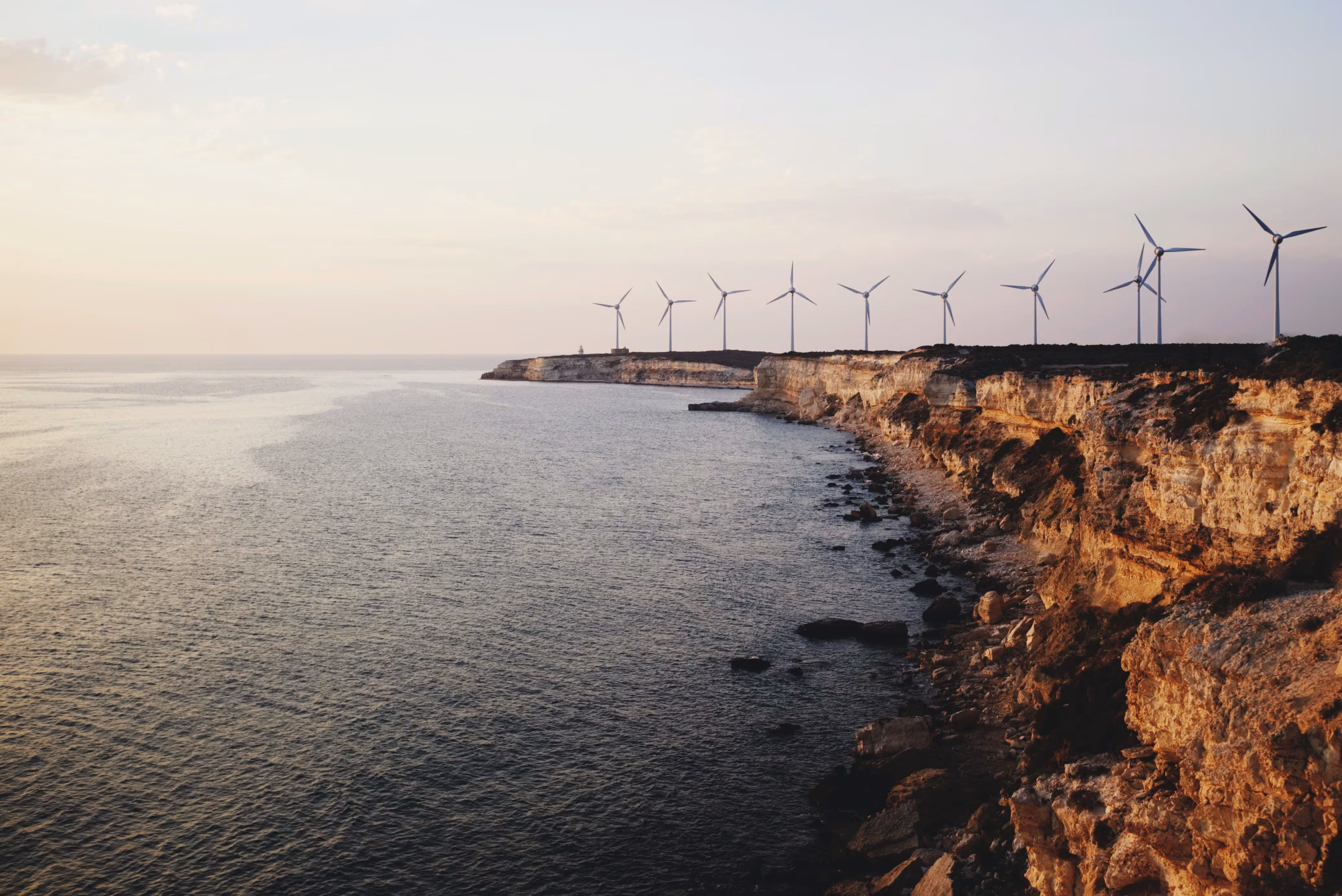 Eine Klippenlandschaft am Meer mit mehreren Windrädern.