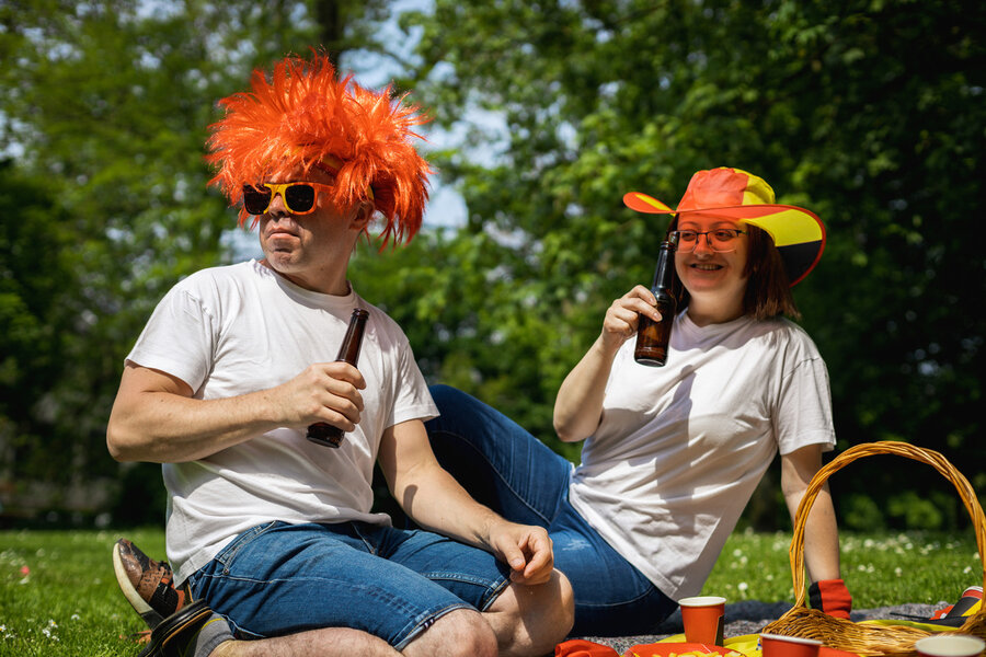 A man and a woman sitting in a park, wearing silly costumes for Instagram