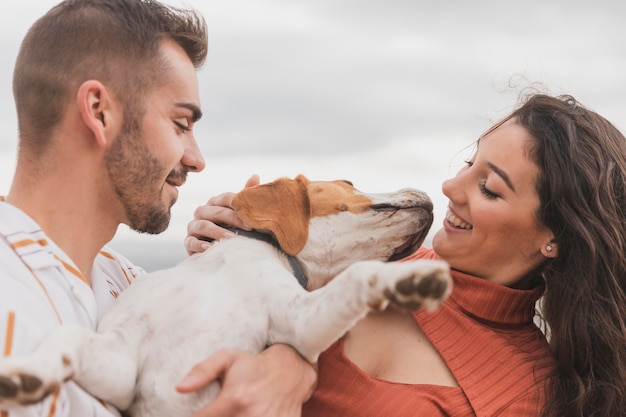 Couple playing with dog in a cloudy weather