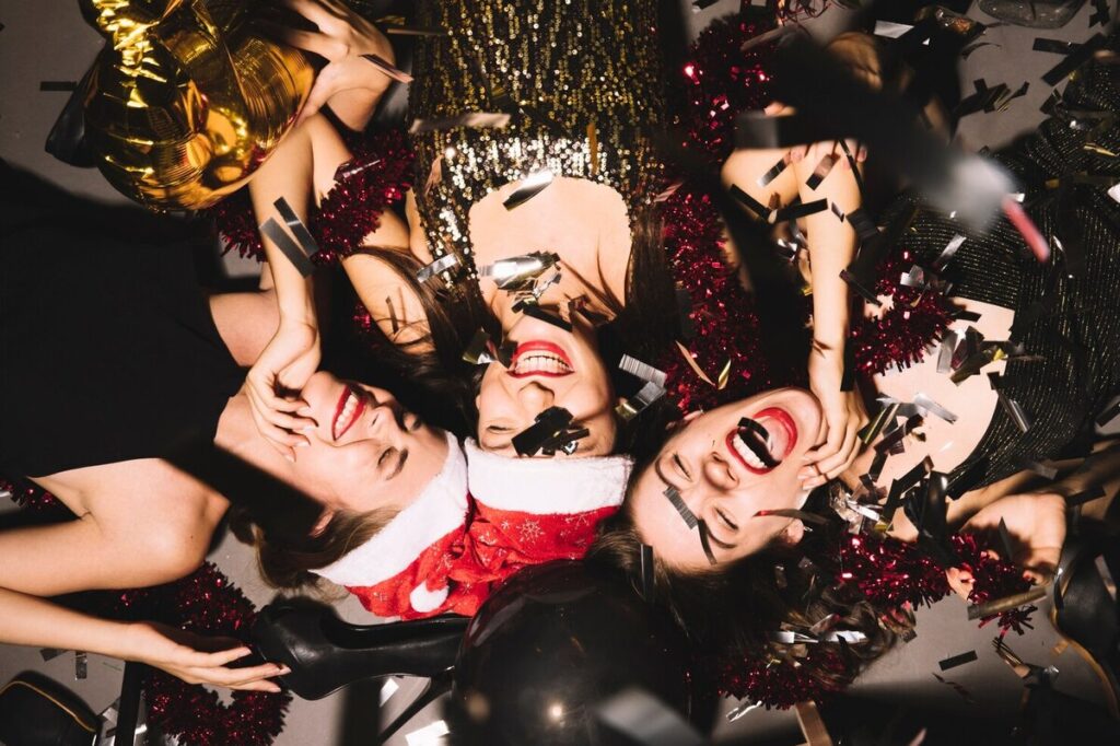 Three girls in the middle of confetti In a New year party