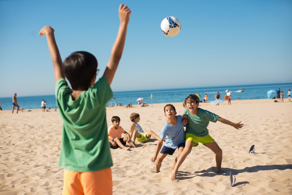 kids having fun on a beach day playing with a ball