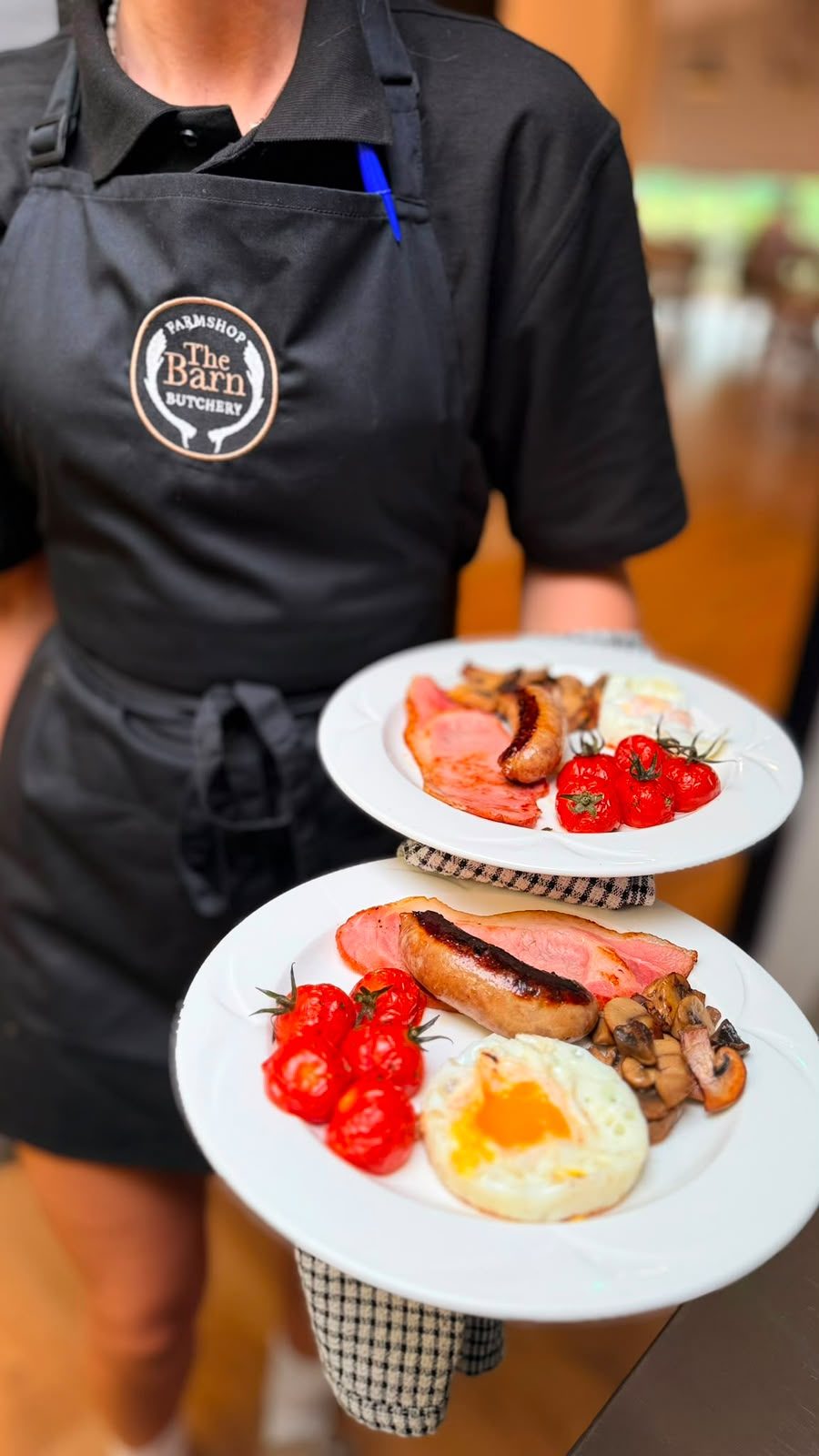 A member of The Barn Butchery team carrying two cooked breakfasts to the table