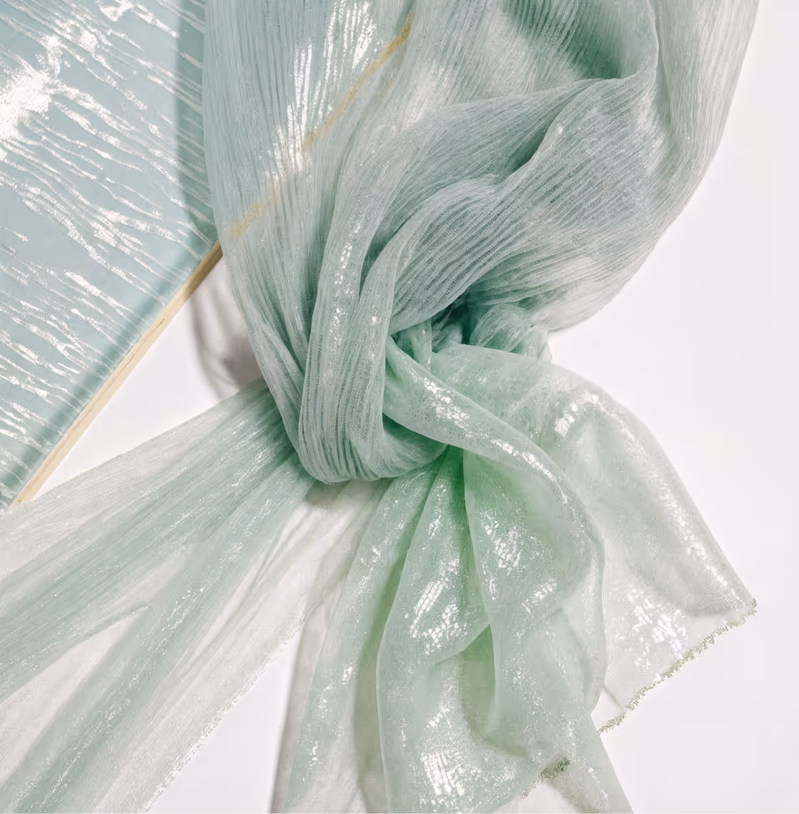 Light green semi-sheer pleated fabric with subtle shimmer, showcasing high-quality textile suitable for sustainable fashion and European apparel production