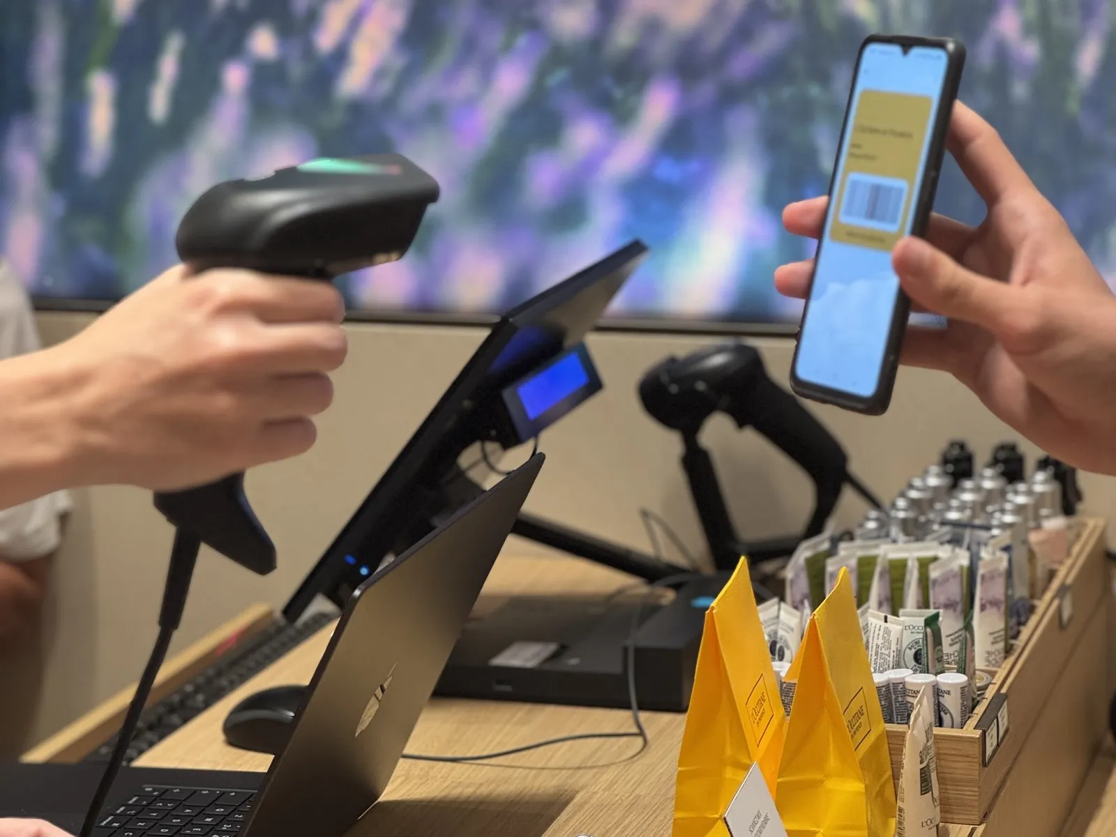 Vendeur scannant la carte de fidélité Google Wallet d'un client avec une douchette en caisse dans une boutique L'Occitane