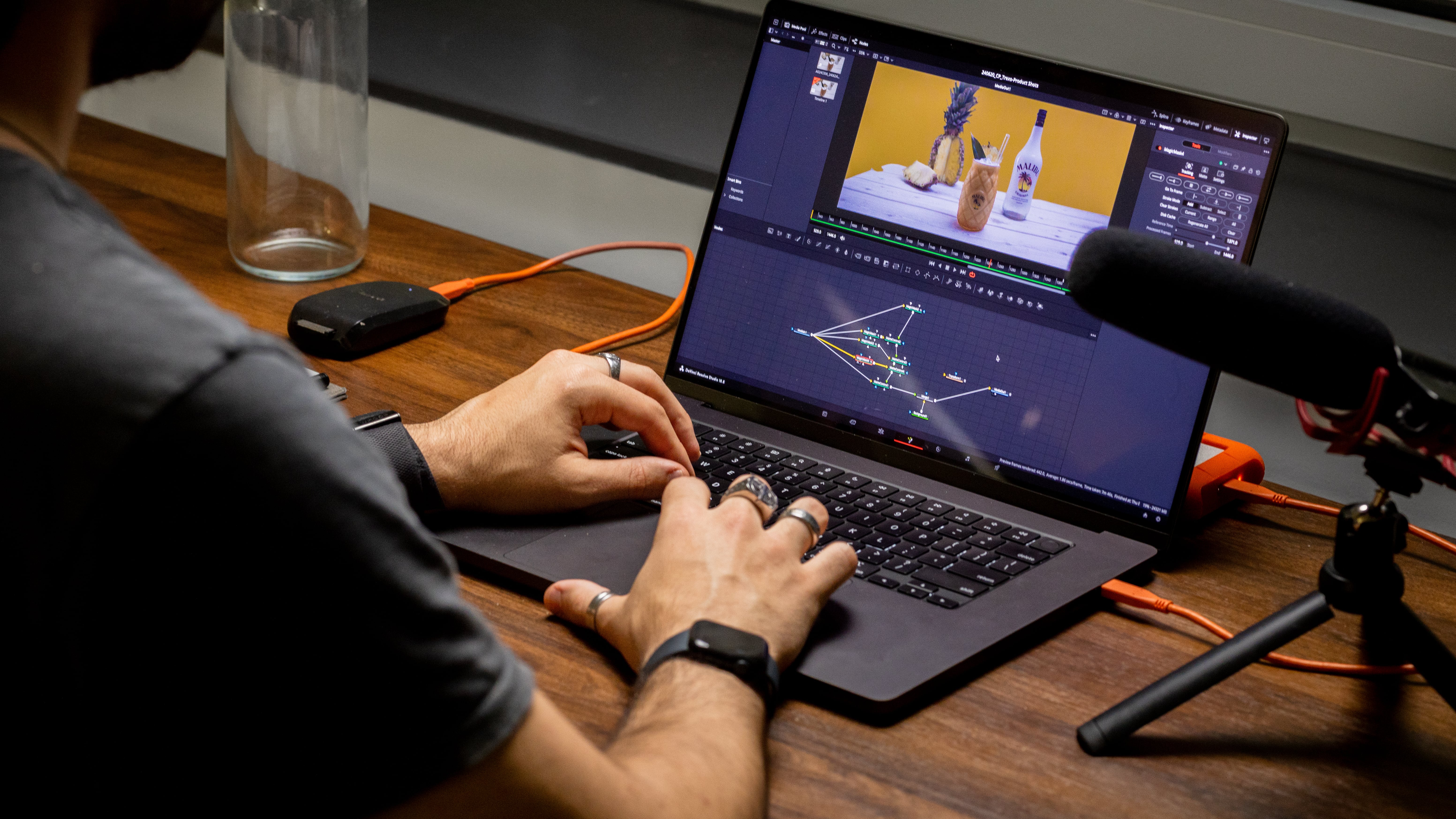 A apple MacBook Pro laptop is on a wooden desk with DaVinci Resolve (an editing software) open as some visual effect composting is happening.