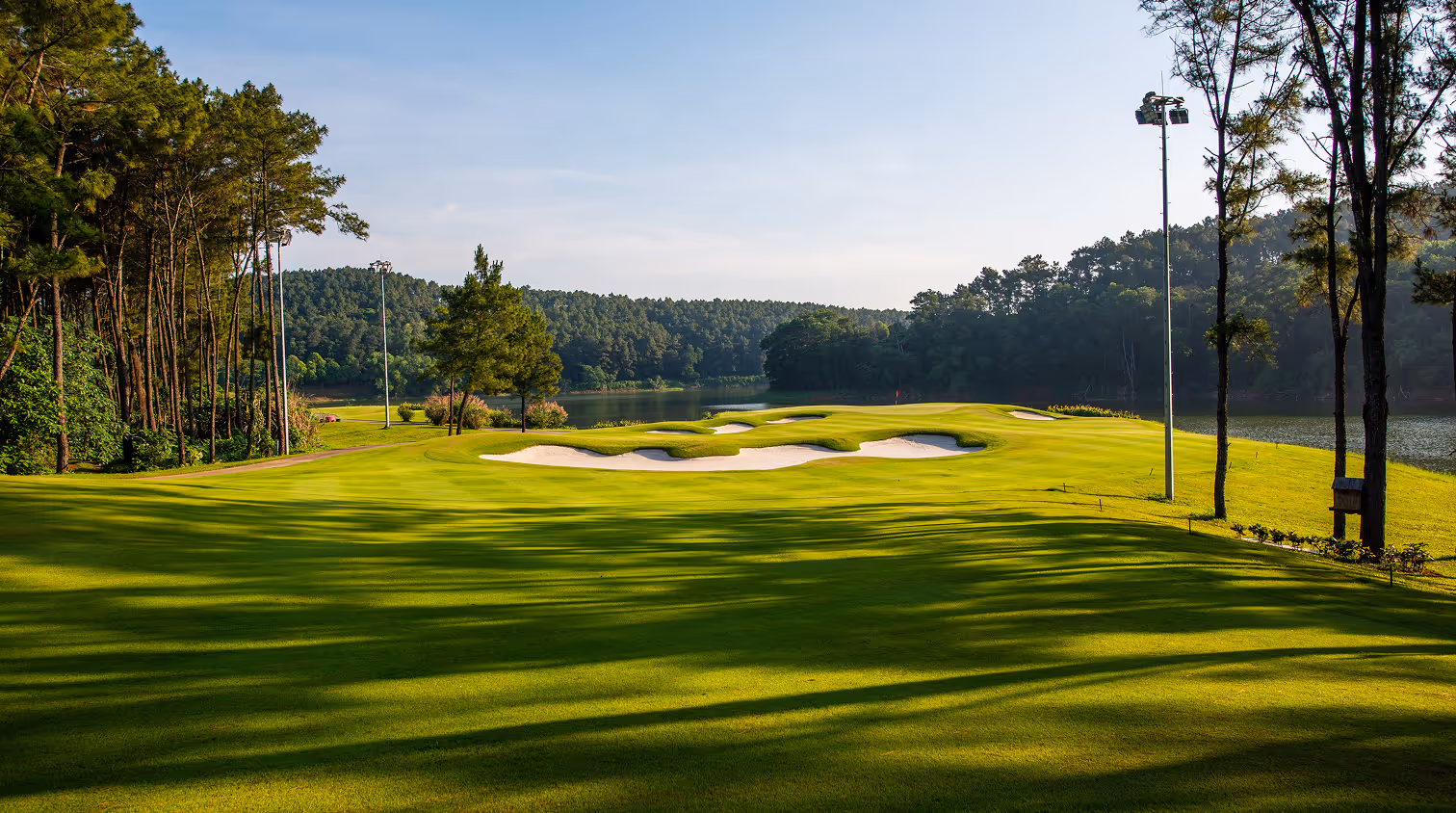 Sunny golf course beside forested lake portraying balance and strategy in financial planning in MI