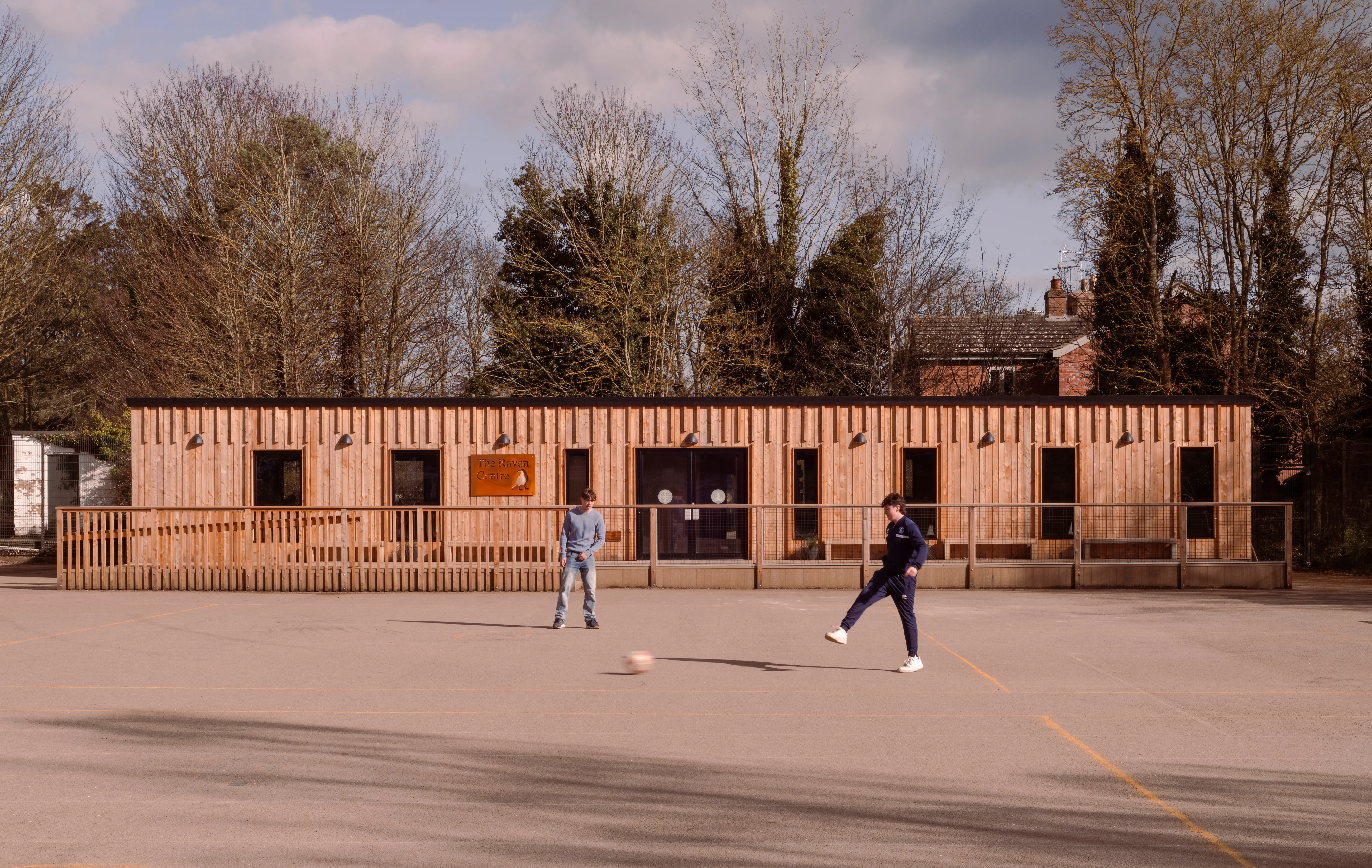 boys playing football infront of modular building
