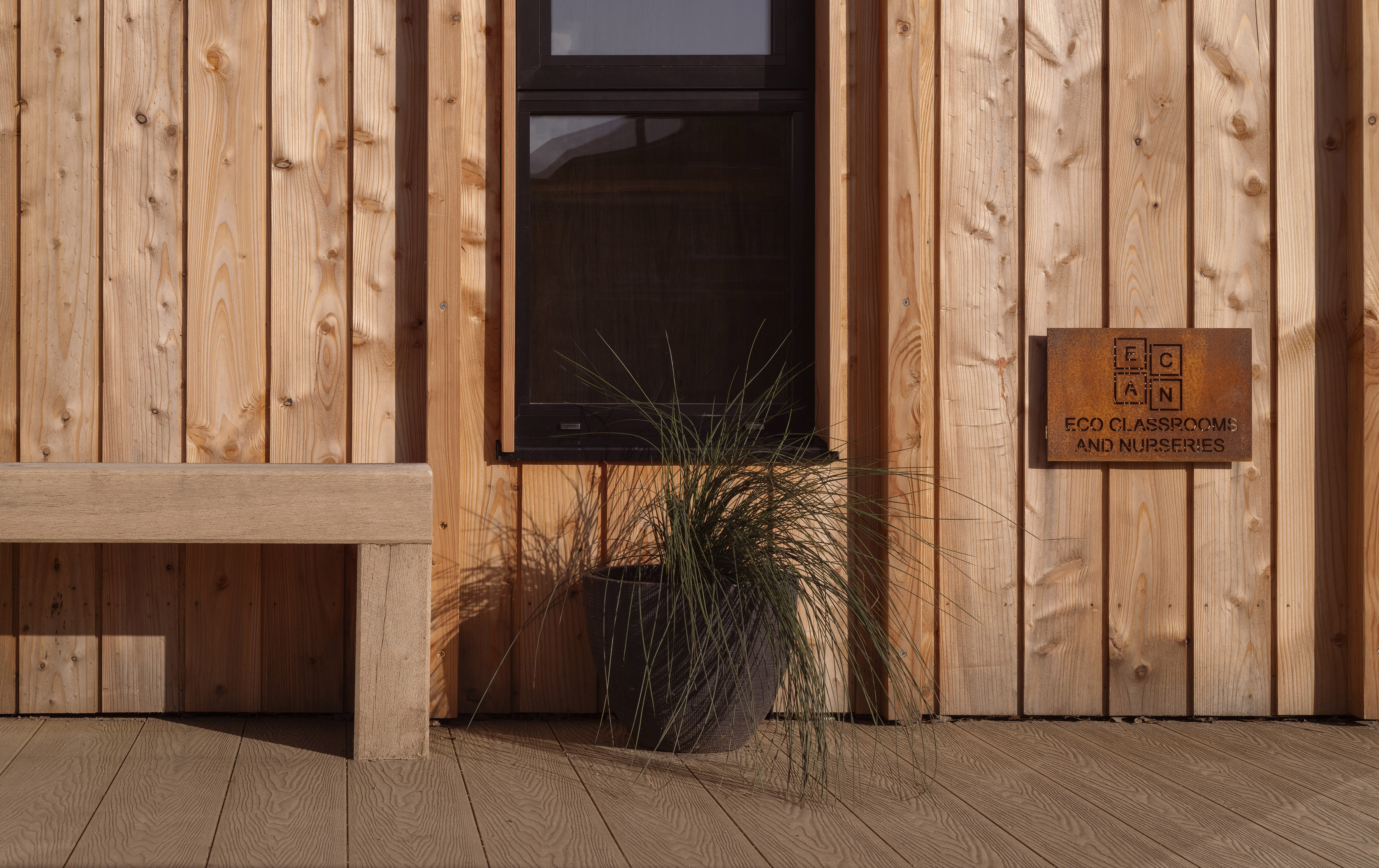 Close-up of timber cladding, a window and the Eco Classrooms and Nurseries plaque at St Benedict's