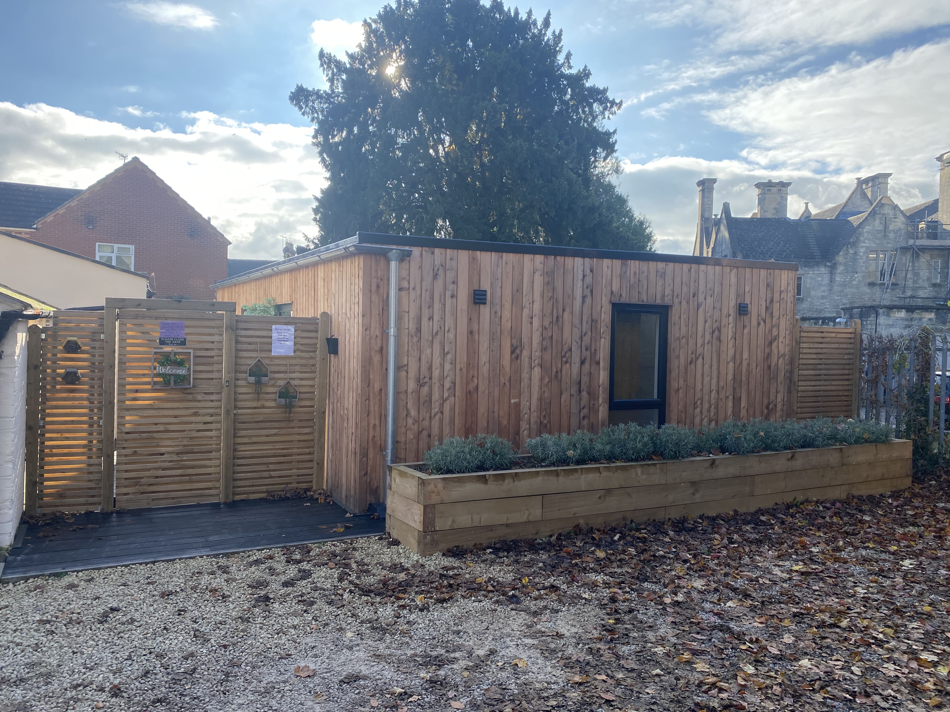 Timber-clad modular building with a gated entrance and raised planter