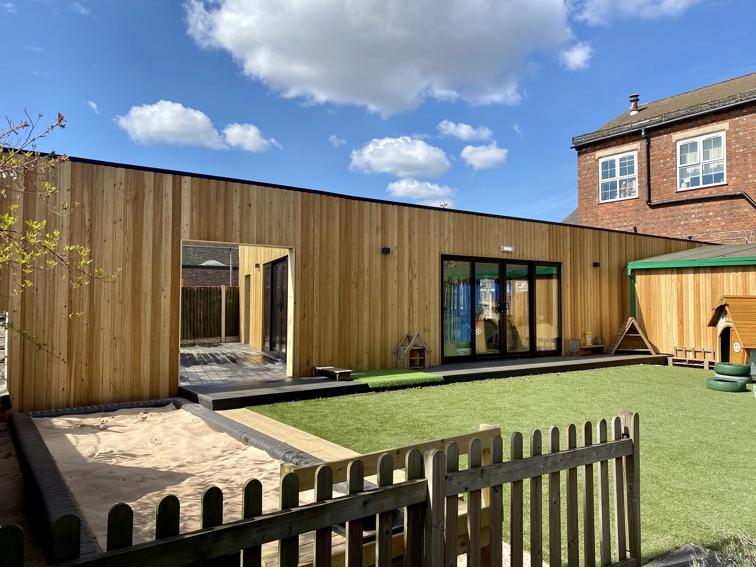 Timber-clad Eastfield Nursery building with an enclosed garden, sandpit and artificial grass