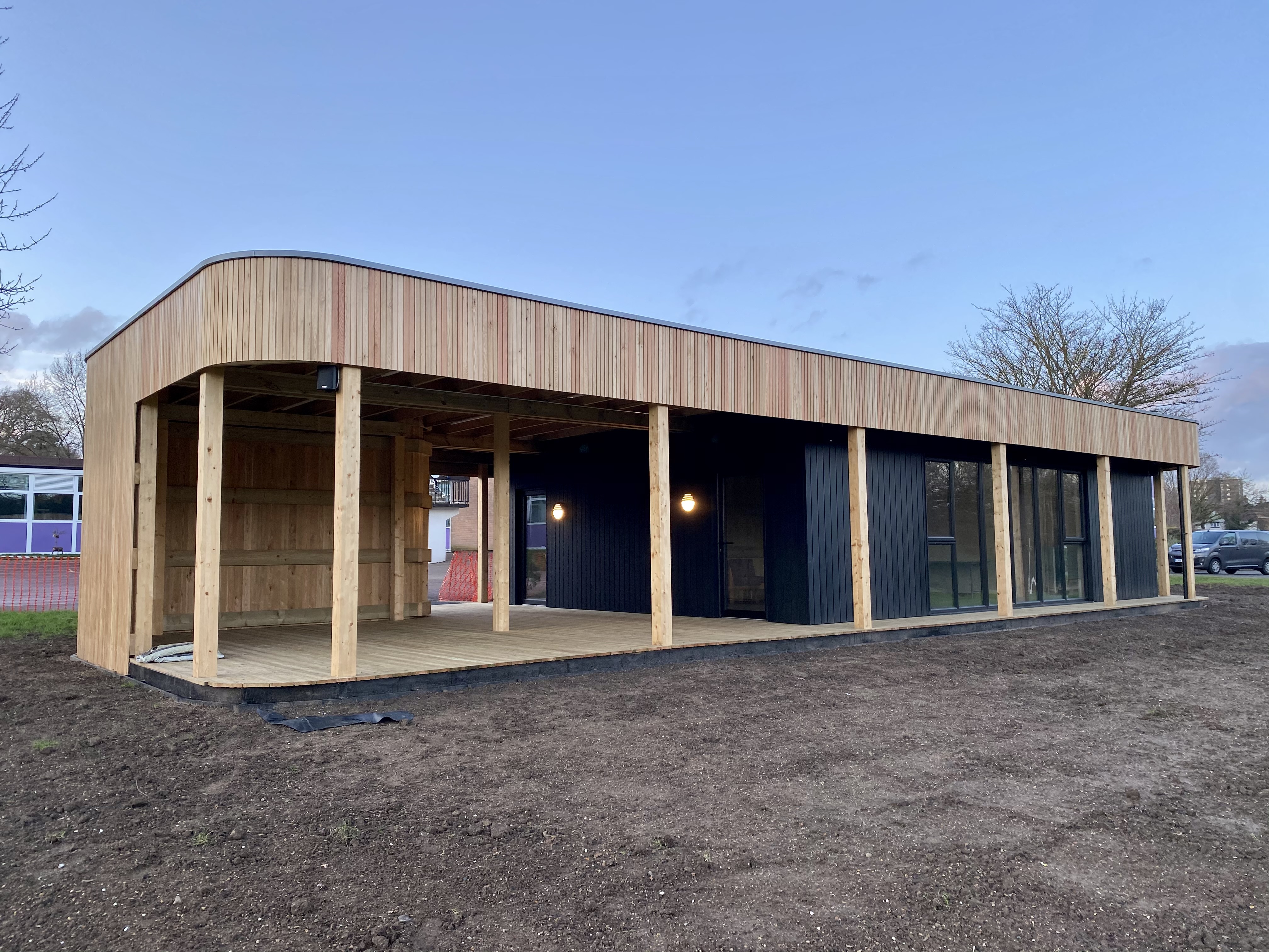 Newly built curved timber pavilion with a covered veranda on a school site