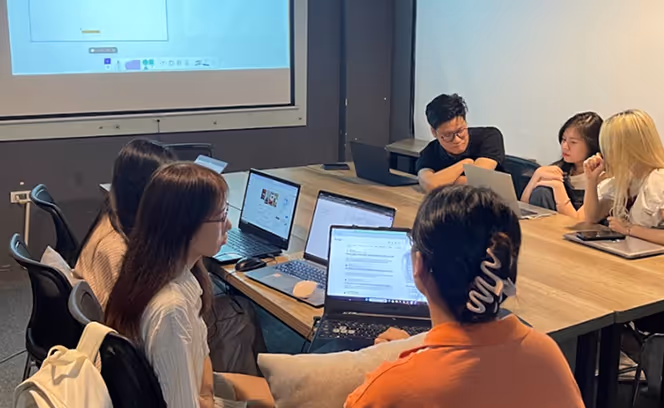 a group of people sitting around a table with laptops