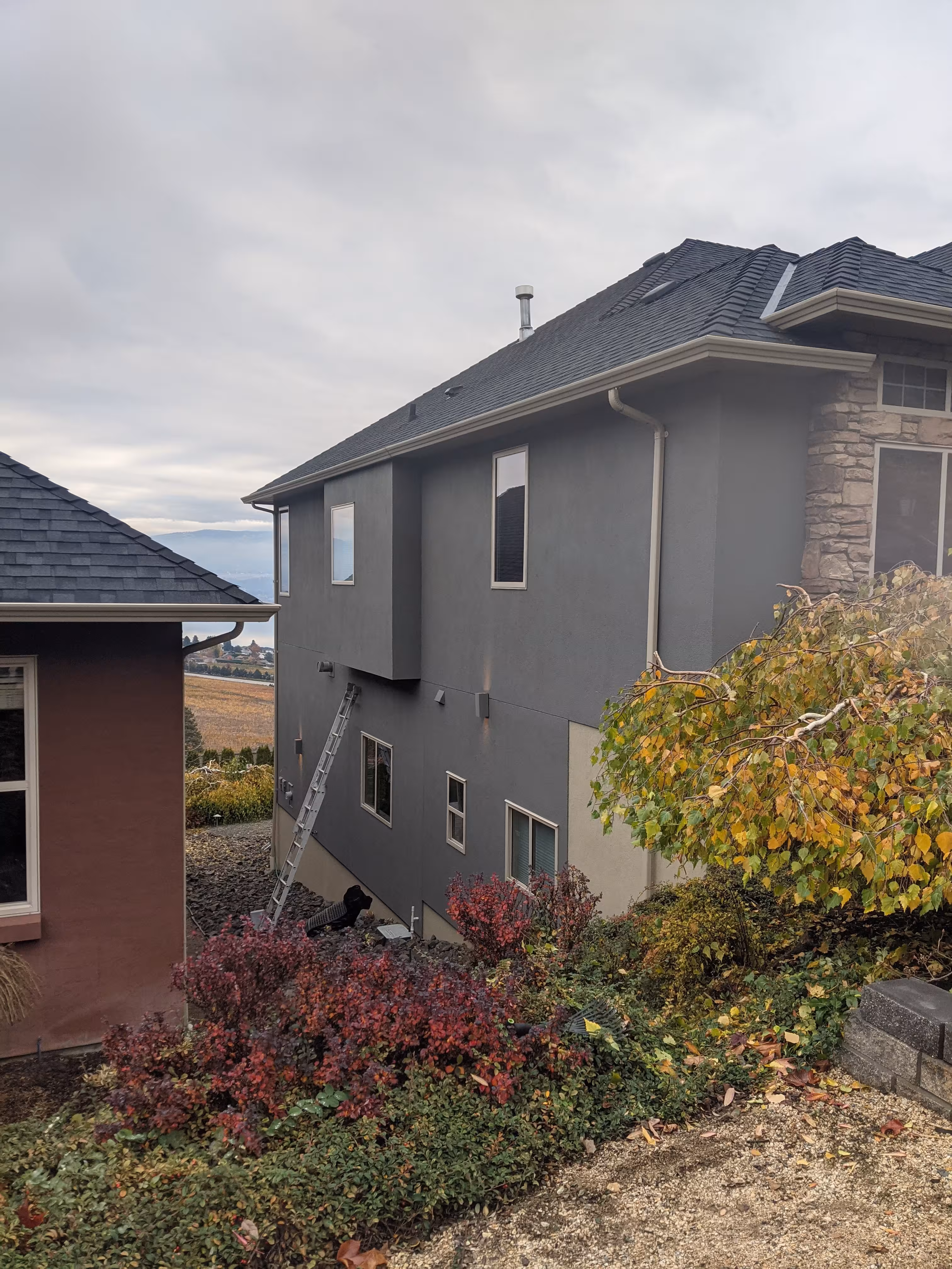 Two-storey stucco home painted in dark grey with an elastomeric coating by The Paint Gurus.