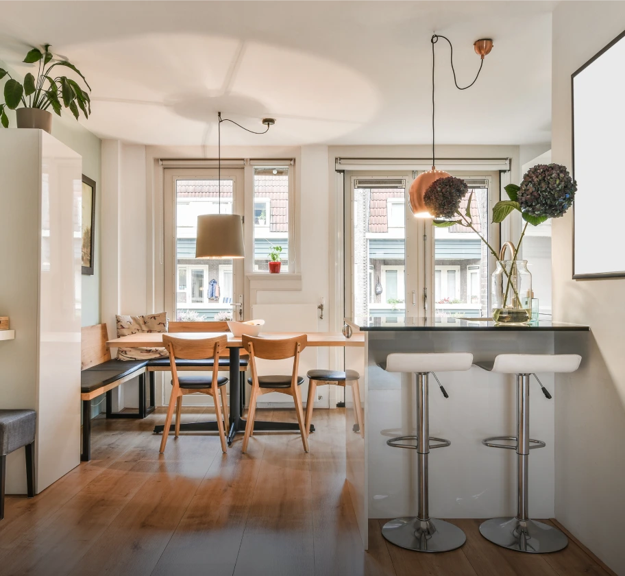 Bright modern kitchen with bar stools and dining table by the window